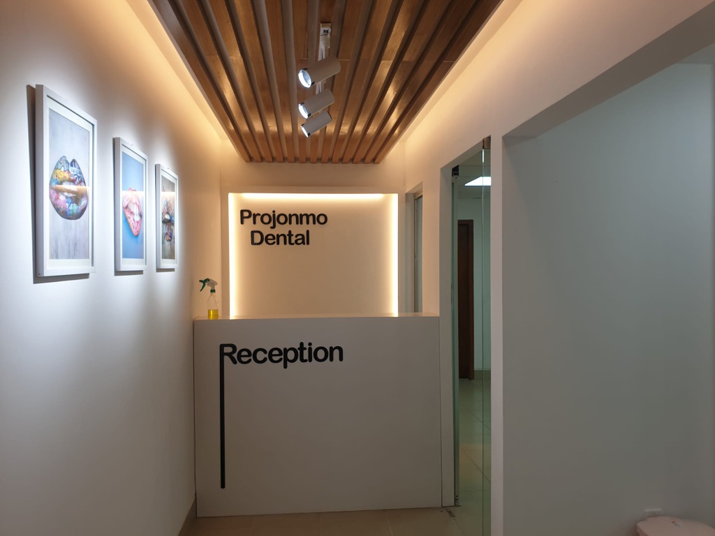 Projonmo Dental reception front view with wood slat ceiling and branding backlight